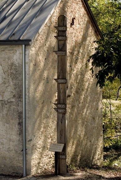 tall wooden pole showing historical flood levels of the Medina River from 1843 to present